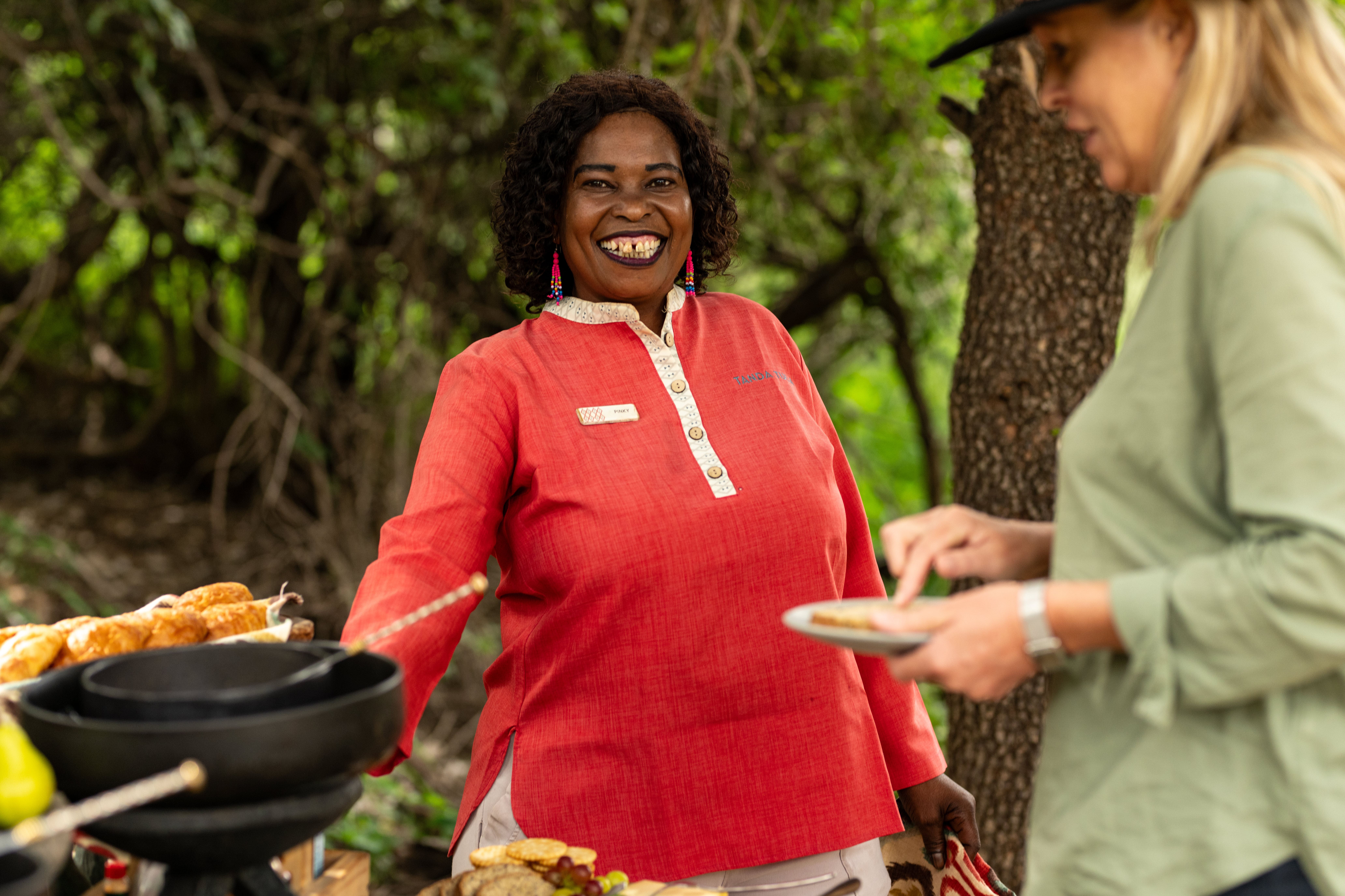 Tanda Tula team member smiling warmly while serving a guest during an outdoor dining experience in the Timbavati.