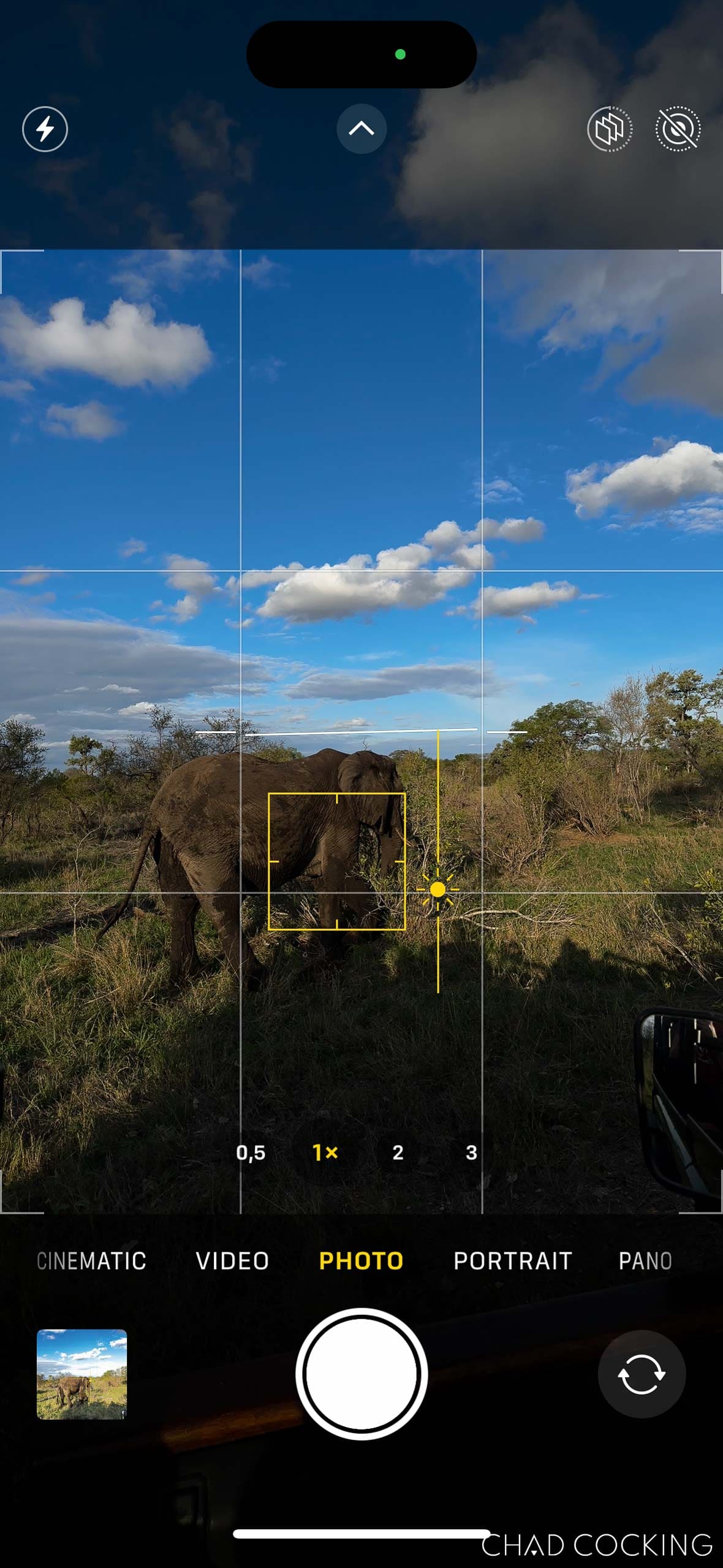 iPhone camera screen showing the exposure slider being moved downward to darken the image.