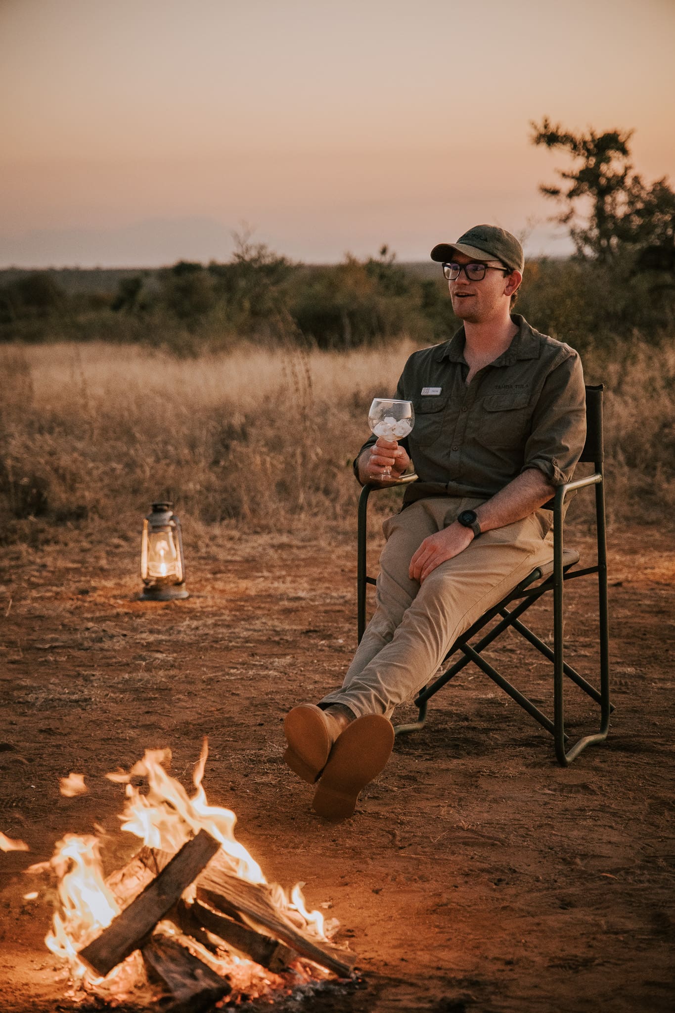 Field guide Tristan Allan-Reynolds relaxing beside a campfire at sunset at Tanda Tula.