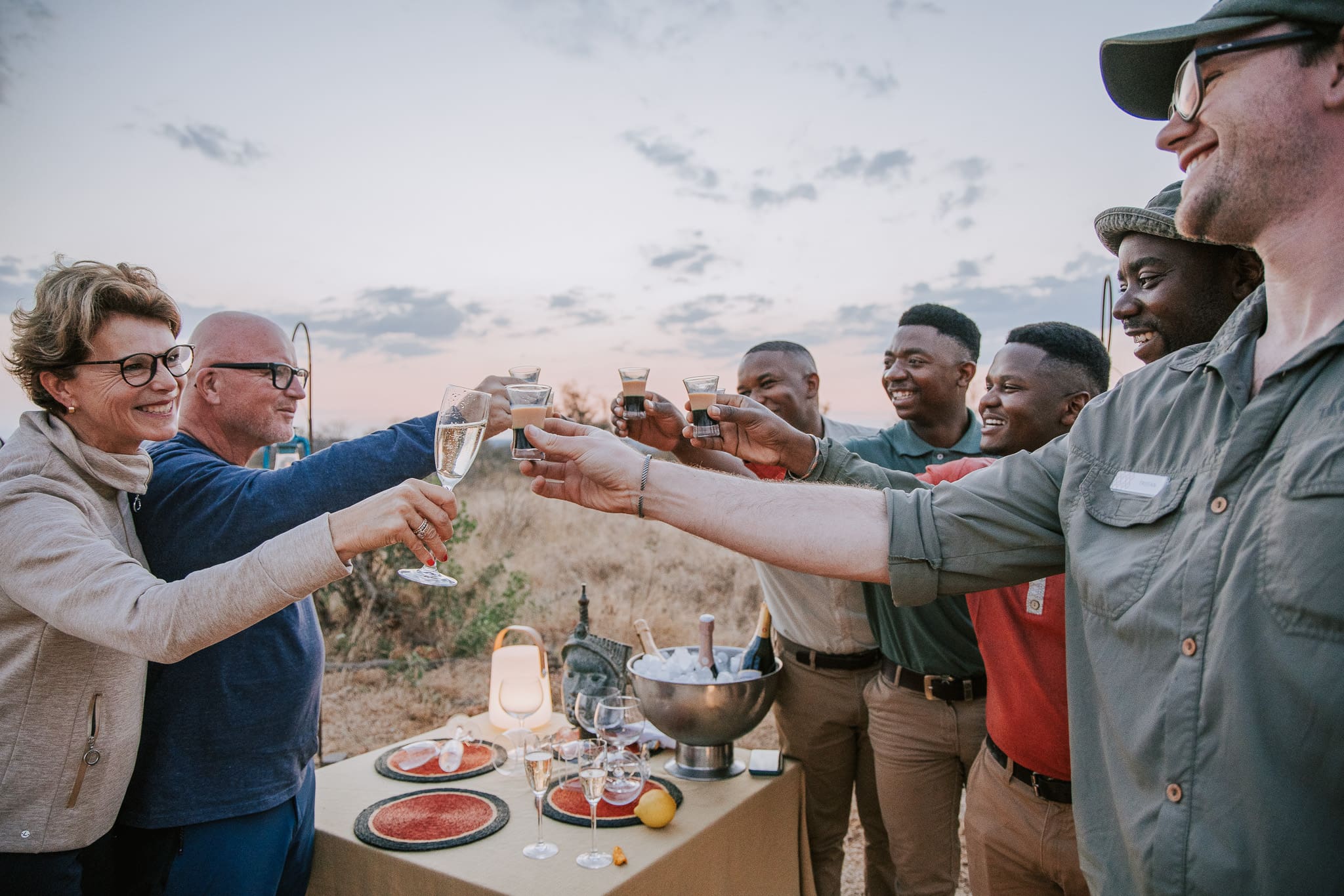 Guests and the Tanda Tula guiding team share a toast during a sunset safari stop.