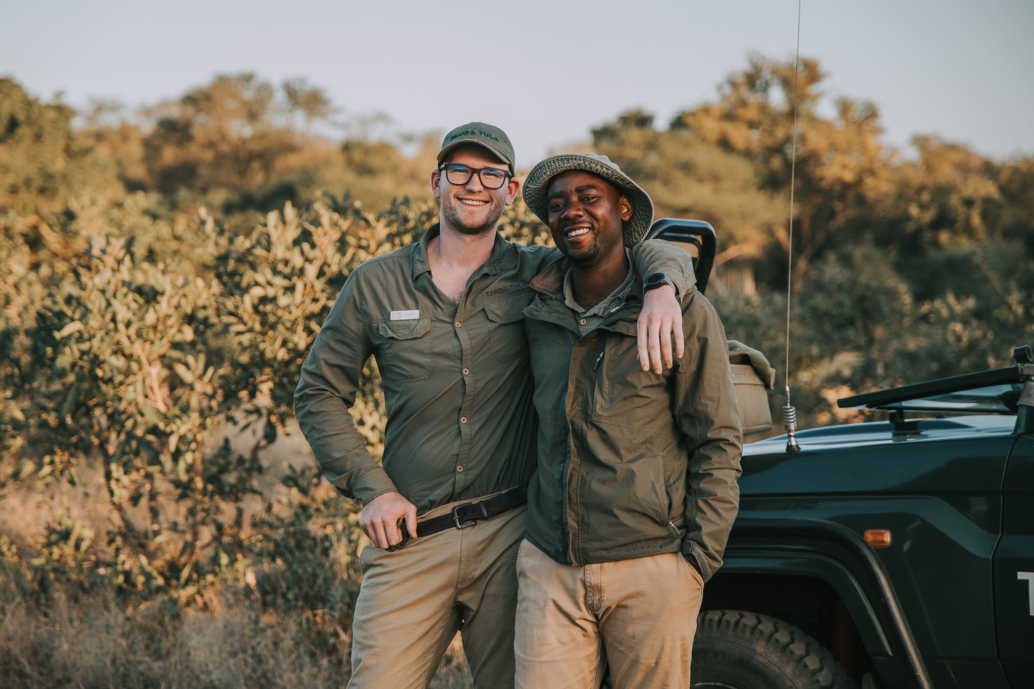 Field guide Tristan Allan-Reynolds standing with tracker Kurisani beside a safari vehicle at Tanda Tula.