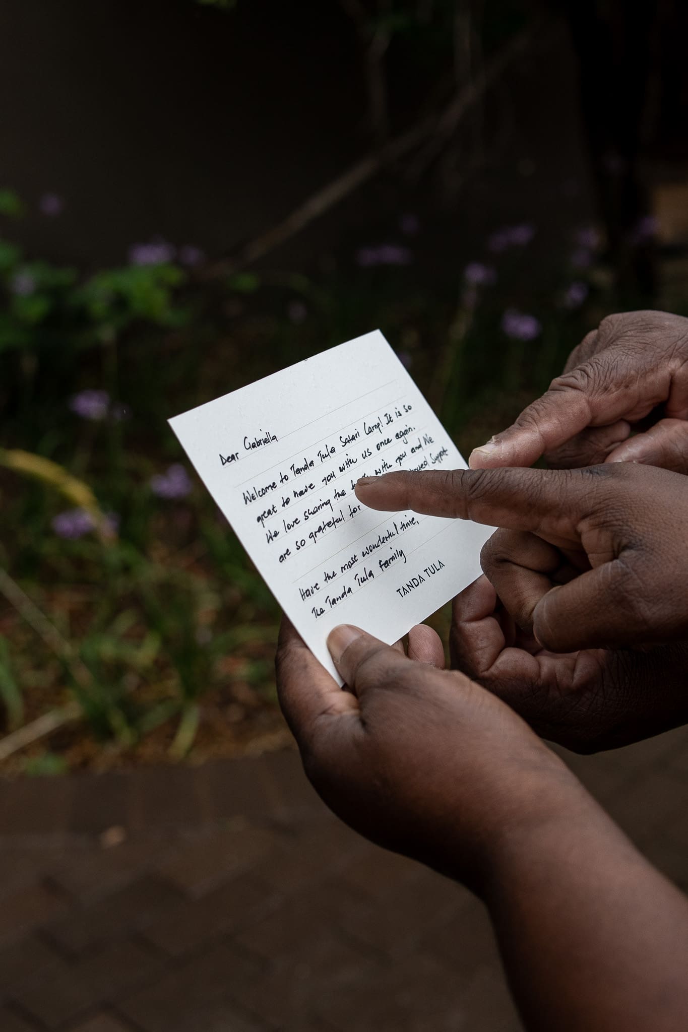 Close-up of two Tanda Tula team members reading a handwritten guest welcome card together.
