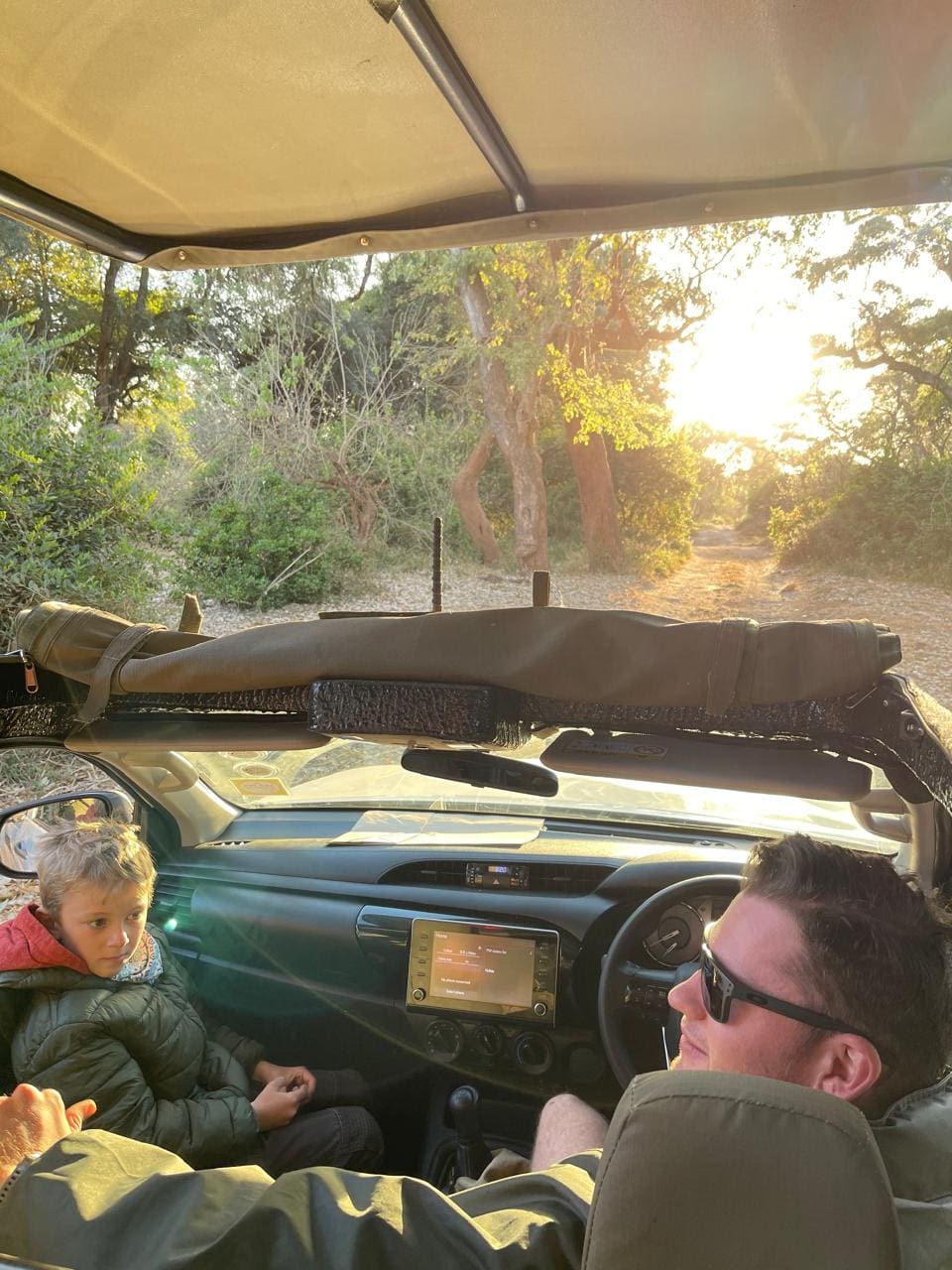 Field guide Tristan Allan-Reynolds listening to a young guest during a safari drive in Pafuri at sunset.